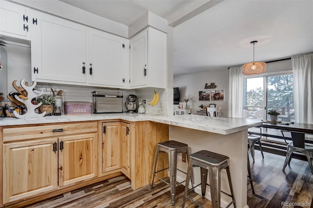 kitchen with a peninsula, dark wood-style flooring, light countertops, tasteful backsplash, and decorative light fixtures