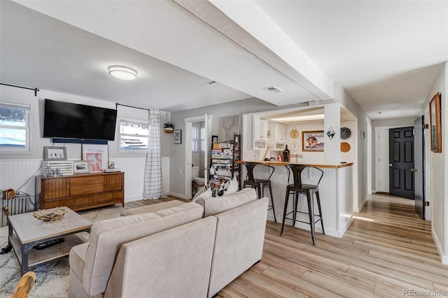 living room featuring light wood-type flooring, baseboards, and visible vents