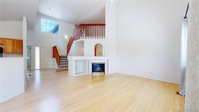 2314 Flagstaff Dr, Longmont, CO 80504 - unfurnished living room with high vaulted ceiling, light wood-type flooring, stairway, and a tiled fireplace