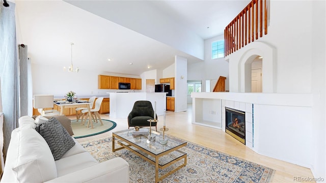 2314 Flagstaff Dr, Longmont, CO 80504 - living room featuring a chandelier, high vaulted ceiling, light wood finished floors, and a fireplace