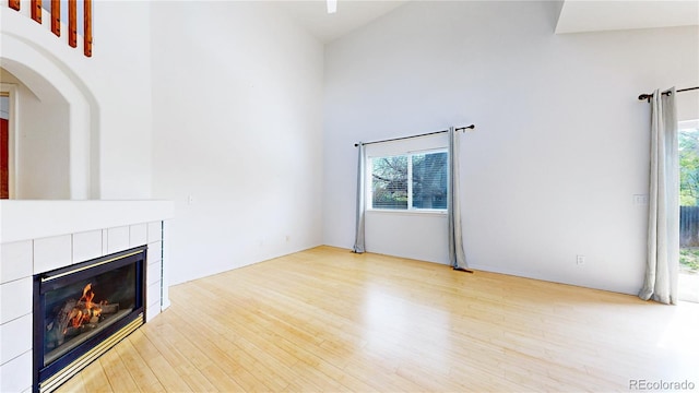 2314 Flagstaff Dr, Longmont, CO 80504 - unfurnished living room with wood finished floors, a towering ceiling, a fireplace, and arched walkways