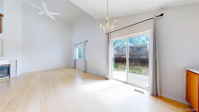 2314 Flagstaff Dr, Longmont, CO 80504 - unfurnished living room featuring high vaulted ceiling, light wood-style floors, a chandelier, ceiling fan, and a tiled fireplace