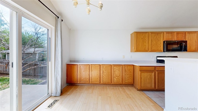 2314 Flagstaff Dr, Longmont, CO 80504 - kitchen with black microwave, light countertops, light wood-style floors, a chandelier, and vaulted ceiling