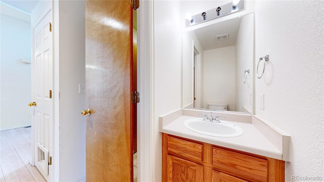 2314 Flagstaff Dr, Longmont, CO 80504 - half bathroom featuring toilet, vanity, and wood finished floors