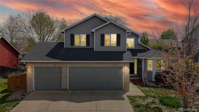 2314 Flagstaff Dr, Longmont, CO 80504 - view of front of property with driveway, brick siding, a shingled roof, fence, and a garage