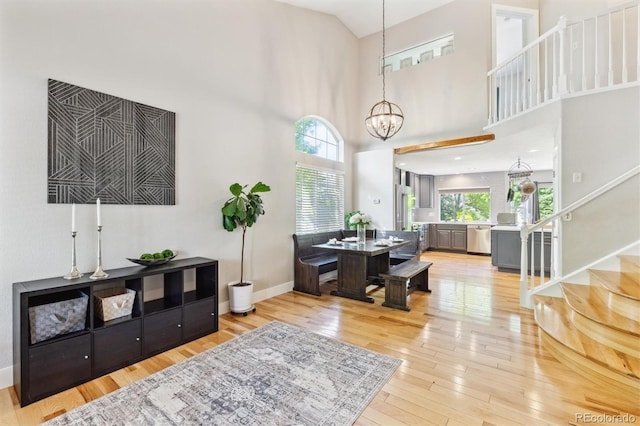 1441 Cherry Pl, Erie, CO 80516 - living room featuring stairway, plenty of natural light, light wood-type flooring, a chandelier, and a towering ceiling