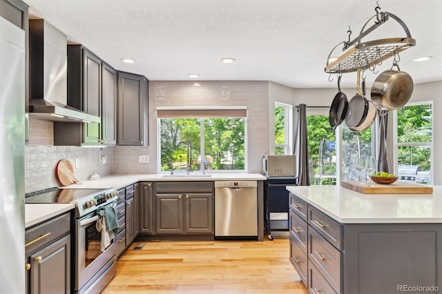 1441 Cherry Pl, Erie, CO 80516 - kitchen featuring appliances with stainless steel finishes, wall chimney exhaust hood, light wood-style floors, plenty of natural light, and recessed lighting