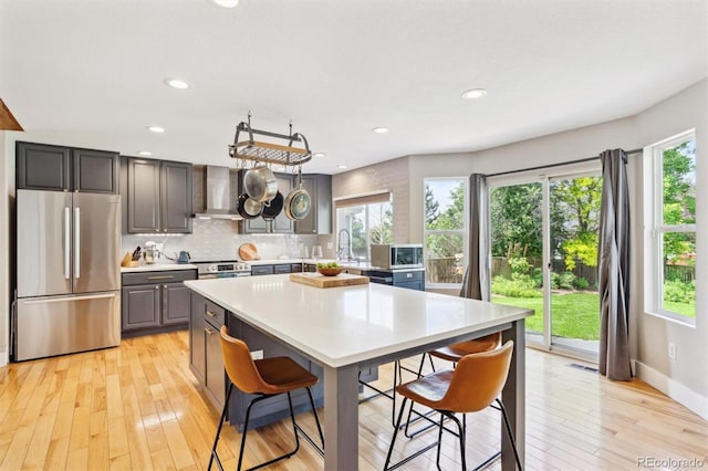 1441 Cherry Pl, Erie, CO 80516 - kitchen featuring stainless steel appliances, wall chimney range hood, a breakfast bar area, healthy amount of natural light, and recessed lighting