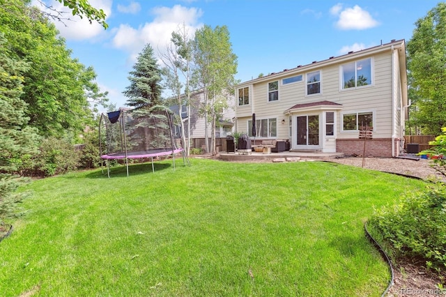 1441 Cherry Pl, Erie, CO 80516 - back of property featuring a trampoline, a patio area, and brick siding