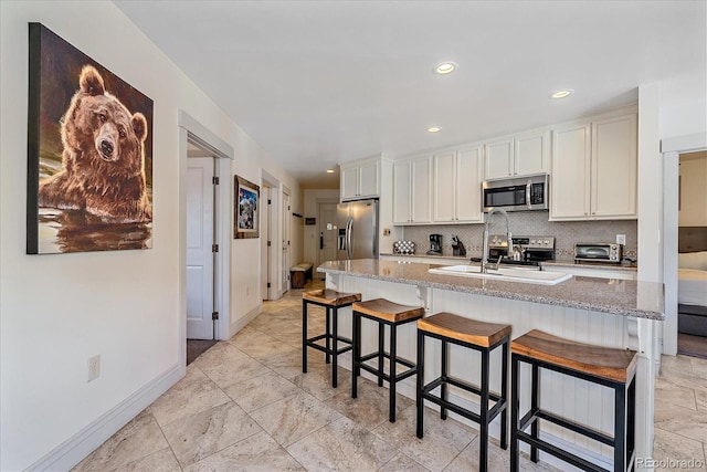 kitchen featuring a kitchen bar, appliances with stainless steel finishes, sink, and white cabinetry