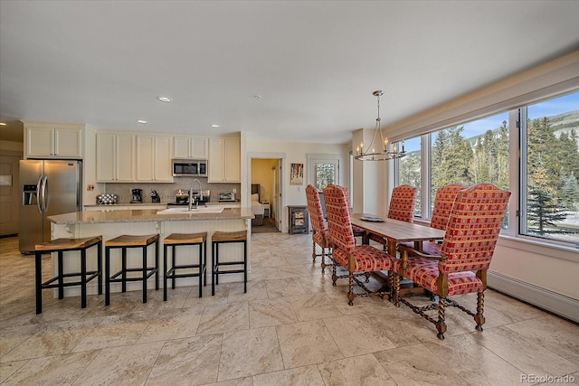 dining area featuring sink, a baseboard radiator, and a notable chandelier