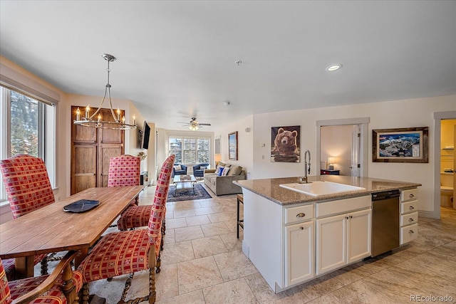 kitchen featuring a center island with sink, dishwasher, ceiling fan with notable chandelier, white cabinets, and sink