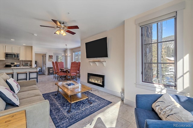 living room with light tile patterned floors and ceiling fan with notable chandelier