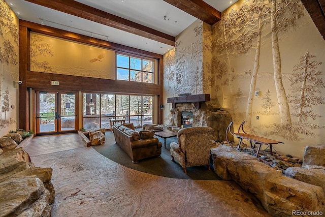 living room featuring a high ceiling, french doors, and a stone fireplace