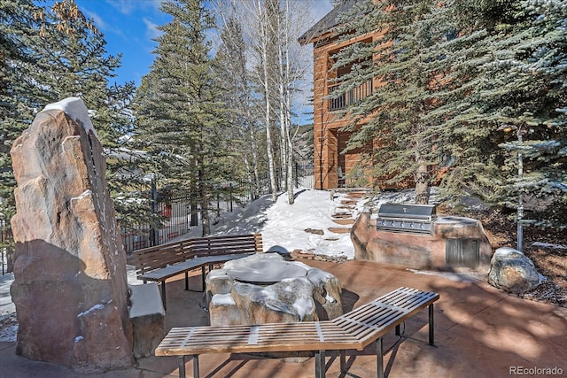 snow covered patio featuring grilling area and exterior kitchen