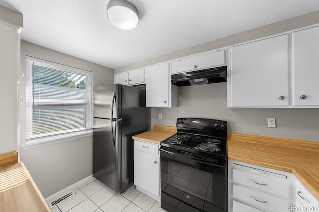 kitchen with light tile patterned flooring, fridge, white cabinetry, and electric range