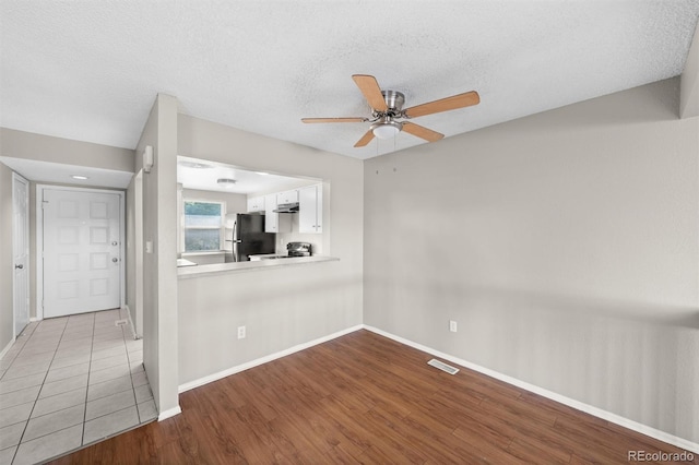 empty room featuring light hardwood / wood-style flooring, a textured ceiling, and ceiling fan