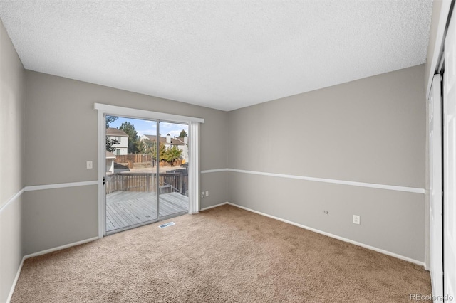 carpeted empty room featuring a textured ceiling