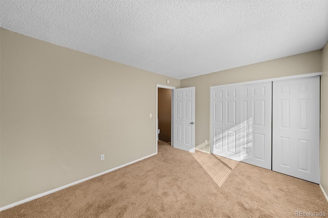 unfurnished bedroom featuring a closet, a textured ceiling, and light carpet