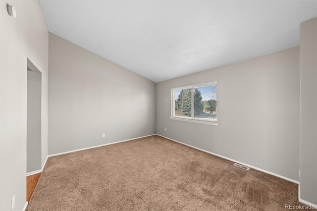 carpeted empty room with vaulted ceiling