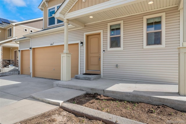 entrance to property featuring concrete driveway, board and batten siding, and a garage