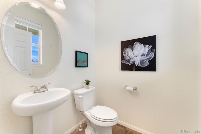 bathroom featuring baseboards, a sink, and toilet