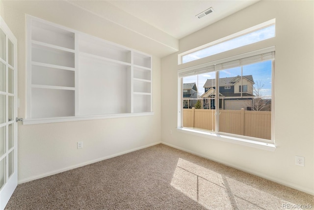 carpeted spare room featuring baseboards and visible vents