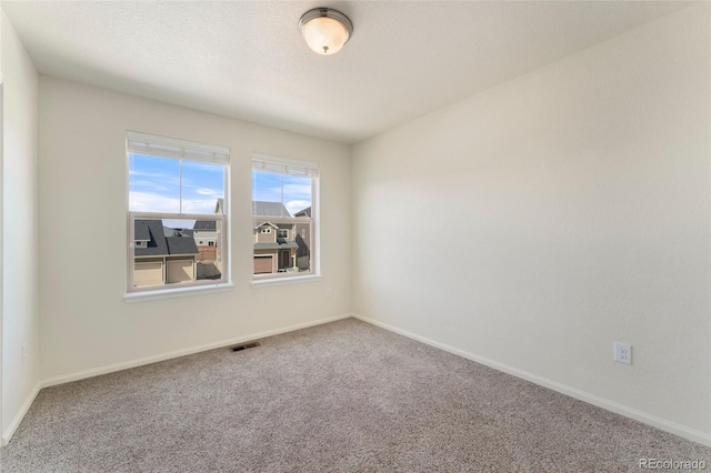carpeted spare room with baseboards and visible vents
