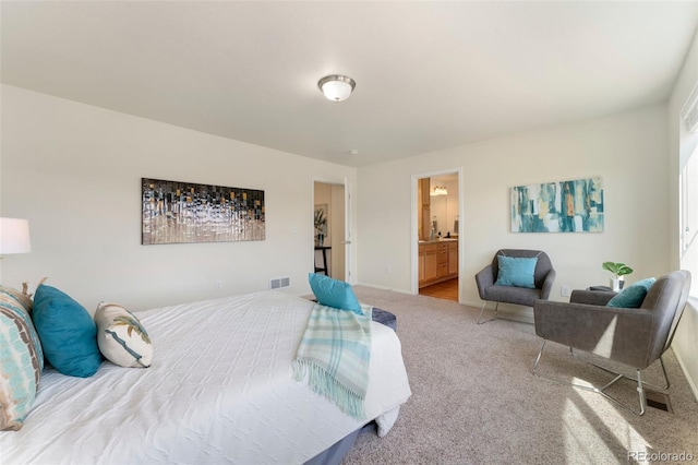 bedroom featuring ensuite bath, visible vents, and carpet