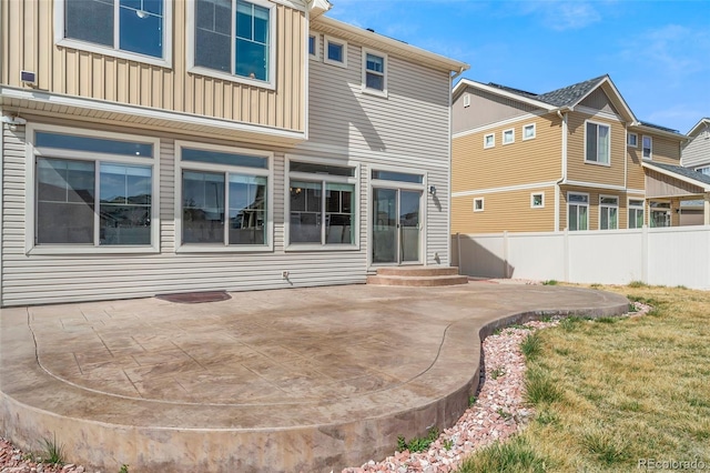 rear view of property with a patio, board and batten siding, entry steps, and fence