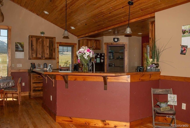 kitchen with a kitchen breakfast bar, hardwood / wood-style flooring, pendant lighting, and wooden ceiling