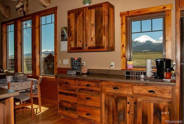 bar with plenty of natural light, a mountain view, and dark wood-type flooring