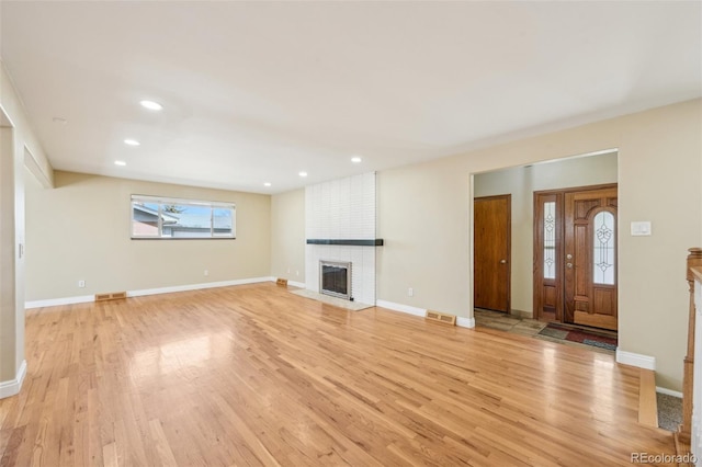 unfurnished living room with visible vents, baseboards, a fireplace, and light wood finished floors