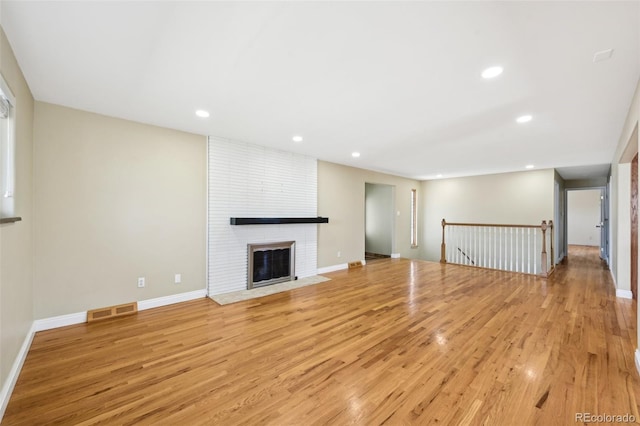 unfurnished living room with light wood finished floors, visible vents, recessed lighting, and a brick fireplace