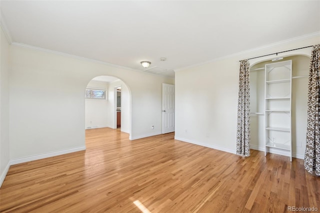 unfurnished room featuring baseboards, arched walkways, ornamental molding, and light wood finished floors