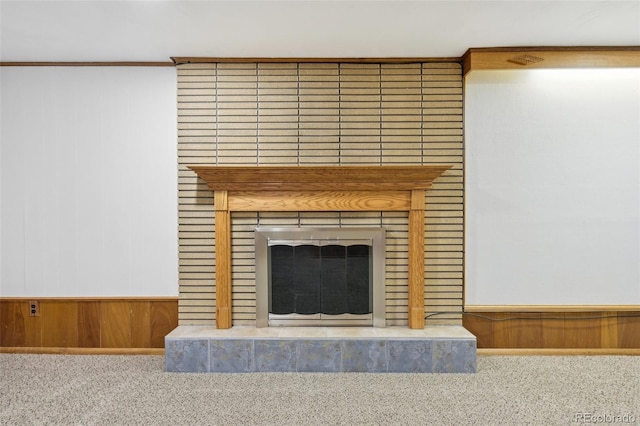 room details with wainscoting, wood walls, a fireplace, and carpet floors