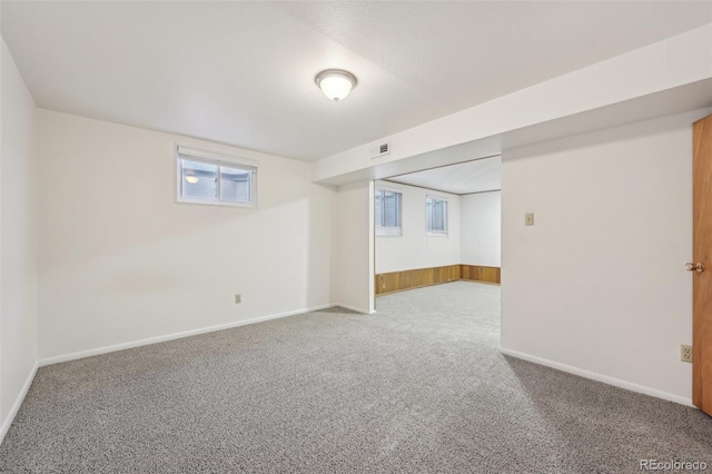 basement featuring visible vents, baseboards, and carpet