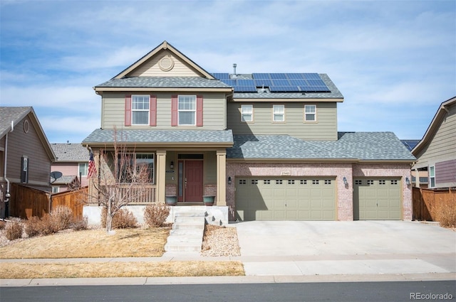 view of front facade with fence, a porch, concrete driveway, roof with shingles, and roof mounted solar panels