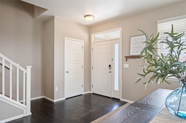 foyer entrance with stairway, wood finished floors, and baseboards