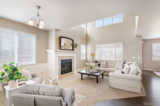 living room featuring baseboards, a fireplace, an inviting chandelier, wood finished floors, and a decorative wall