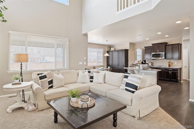 living area with recessed lighting, baseboards, and a towering ceiling