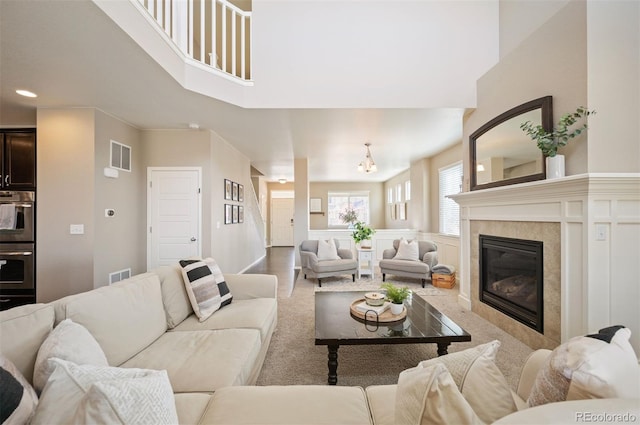 carpeted living room with a tiled fireplace, visible vents, and recessed lighting