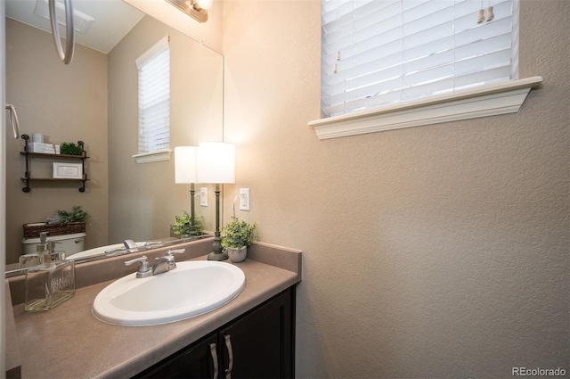 half bath featuring vanity and a textured wall