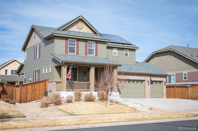 view of front of property with fence, covered porch, an attached garage, a shingled roof, and solar panels