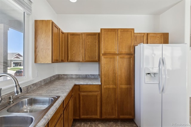 719 Elk Mountain Dr, Severance, CO 80550 - kitchen featuring white fridge with ice dispenser, a sink, brown cabinetry, and light countertops