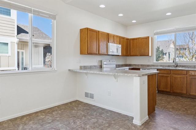 719 Elk Mountain Dr, Severance, CO 80550 - kitchen with white appliances, brown cabinetry, a kitchen bar, a sink, and light countertops