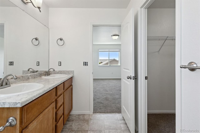 719 Elk Mountain Dr, Severance, CO 80550 - bathroom featuring double vanity, baseboards, and a spacious closet