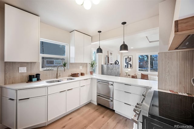 kitchen featuring light hardwood / wood-style floors, sink, hanging light fixtures, and white cabinets