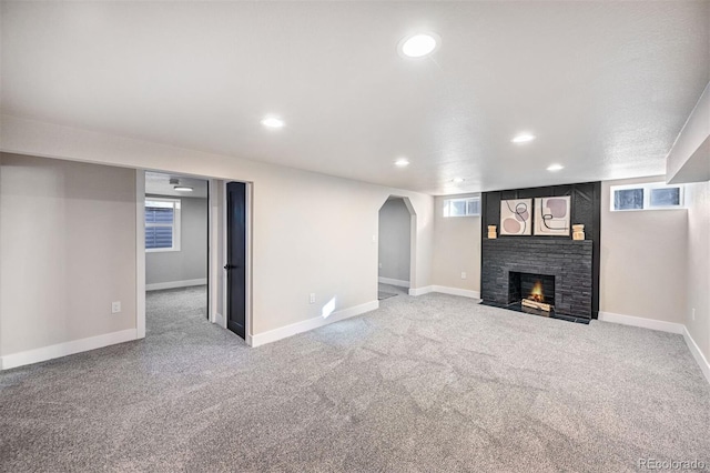 unfurnished living room featuring a brick fireplace and light colored carpet