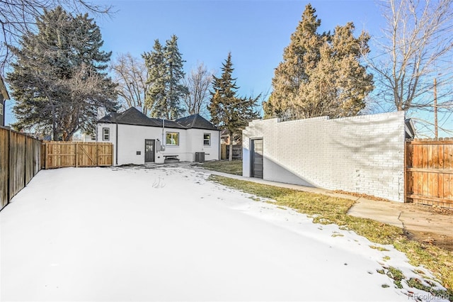 snow covered rear of property featuring central air condition unit